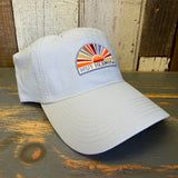 Light blue grey cap with colorful sunset design and Muy Hermosa text on a wooden surface