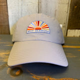 Beige cap with colorful Muy Hermosa patch on a wooden surface