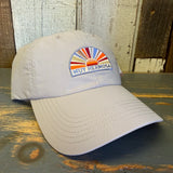 Beige cap with colorful Muy Hermosa patch on a wooden surface