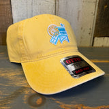 Yellow cotton dad hat with lifeguard tower patch, placed on a wooden surface.