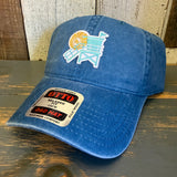 Sky blue cotton dad hat, 6-panel low profile, lifeguard tower motif, displayed with tags on wooden surface.