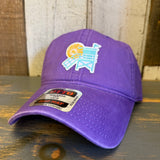 Purple cotton dad hat featuring a lifeguard tower design, placed on a wooden surface.
