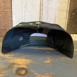 Camo 6-panel cotton hat displayed upside down on rustic wood, highlighting color and material.