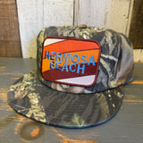 Green camo 5-panel hat with a GOLF CARTS & YOGA PANTS patch, displayed on a rustic wooden surface.