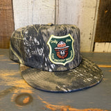 5-panel surf camo hat featuring a gold embroidered Smokey Bear patch; durable fabric, suitable for outdoor wear.