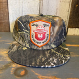 Green camo 5-panel hat with Smokey Bear graphic, suitable for outdoor wear.