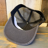 Gray mesh 6-panel trucker hat displayed upside down on a weathered wooden surface.