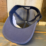 Faded midnight navy trucker hat with mesh back, upside down on rustic wood surface.
