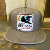 Faded grey 6-panel mesh trucker cap with fabric front and rectangular text patch.