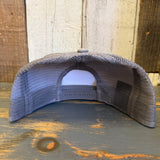 Faded grey 6-panel trucker hat with snapback, mesh back visible, displayed on a wooden surface.