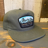 Cypress green 5-panel hat with Grand Teton National Park 1929 embroidery, displayed on a wooden surface.