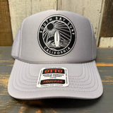 Grey high crown trucker hat with black patch, mesh panels, and OTTO sticker on the brim. Suitable for casual wear.