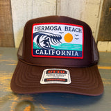 Brown high crown trucker hat with mesh back and The Perfect Wave patch featuring a surfer graphic.
