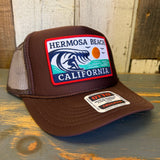 Brown high-crown trucker hat with adjustable snapback; mesh back, cotton front panel. Suitable for casual wear.