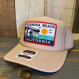 Khaki high crown trucker hat with breathable mesh and patch featuring a wave, sun, and palm trees. For casual outdoor use.
