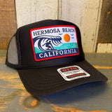 High crown trucker hat with mesh back, curved brim, and surfer patch. Ideal for sunny days at the beach.