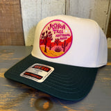 Dark green and natural 5-panel cap with Joshua Tree patch, displayed on a wooden surface. Canvas material.