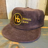 Java brown corduroy hat with yellow logo, adjustable brass clasp, suitable for outings and everyday wear.