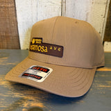 Wheat brown five-panel cap made of fabric, featuring HERMOSA AVE, displayed on a rustic wooden surface.