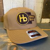 Wheat brown 5-panel cap with patch and OTTO sticker, displayed on a wooden surface.