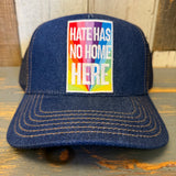 Navy premium denim trucker hat with gold stitching displayed on a wooden surface.