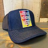 Navy and gold denim trucker hat rests on a wooden surface, highlighting its casual, everyday style and sturdy material.