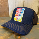 Navy denim trucker hat with gold stitching, displayed on a wooden surface. Suitable for casual wear.