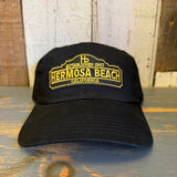 Black cotton dad hat, 6-panel low profile, with white text on front, placed on rustic wooden planks.