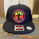 Black snapback hat with a volleyball patch and stickers, displayed on a wooden surface.