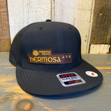Black 6-panel snapback cap with adjustable closure, shown on a wooden surface.