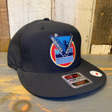 Black 6-panel polyester snapback hat with volleyball patch, displayed on a wooden background.