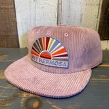 Pink corduroy hat displayed on wood surface, suitable for everyday wear. Inspired by the style of Hermosa Beach.
