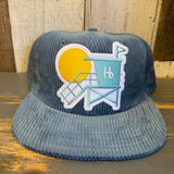 Slate blue corduroy lifeguard tower hat displayed on a wooden surface.