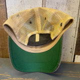 Green underbill trucker cap displayed inside out on wooden surface; mesh material visible.