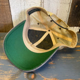 Interior of a green-billed trucker cap on rustic wood, showing mesh back and fabric front panel.