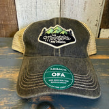 Black and khaki six-panel trucker cap with front patch and green LEGACY OFA sticker, mesh back for casual wear.