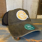 Black six-panel trucker cap with mesh back, sunburst logo, and green Legacy OFA sticker on the brim.