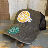 A black and white six-panel trucker cap with mesh back sits on a wooden surface, suitable for casual outdoor use.
