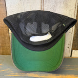 Black trucker cap, displayed upside down to show its green underside and adjustable strap. Mesh material visible.
