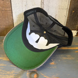 Black mesh trucker cap with green brim and classic logo, displayed on a rustic wooden surface.