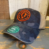 Navy camo and java six-panel trucker cap with orange patch; suitable for casual outdoor wear.