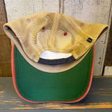 Trucker cap with green bill, beige mesh back, red trim, and navy/khaki panels; casual outdoor wear.