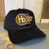 Black corduroy baseball cap on a wooden surface.