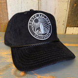 Black corduroy cap with a patch featuring a surfboard and sun design; casual headwear suitable for everyday use.