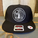 Black 5-panel snapback hat with embroidered SOUTH BAY SURF design, displayed on a wooden surface.