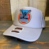Grey mesh trucker hat with volleyball theme rests on rustic wooden surface.
