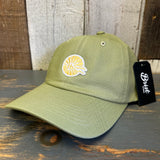 Desert green cotton dad hat with yellow sun logo and black tag, displayed on wooden surface.