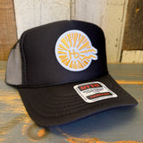 Black high crown trucker hat with classic logo, made of mesh and fabric, resting on a wooden surface.