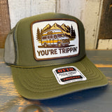Olive green high-crown trucker hat with mesh back, featuring a patch of a van and mountains. Suitable for casual wear.
