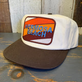 Two-tone Java and natural workhorse hat with patch, displayed on a wooden surface.